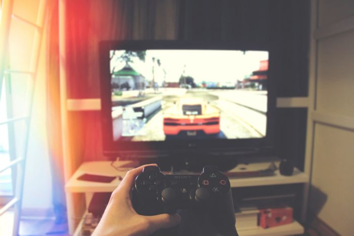 Hand mit Spielekonsole vor Fernseher